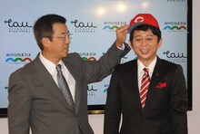 達川光男（左）に広島東洋カープの帽子をかぶせてもらう有吉弘行（右）。