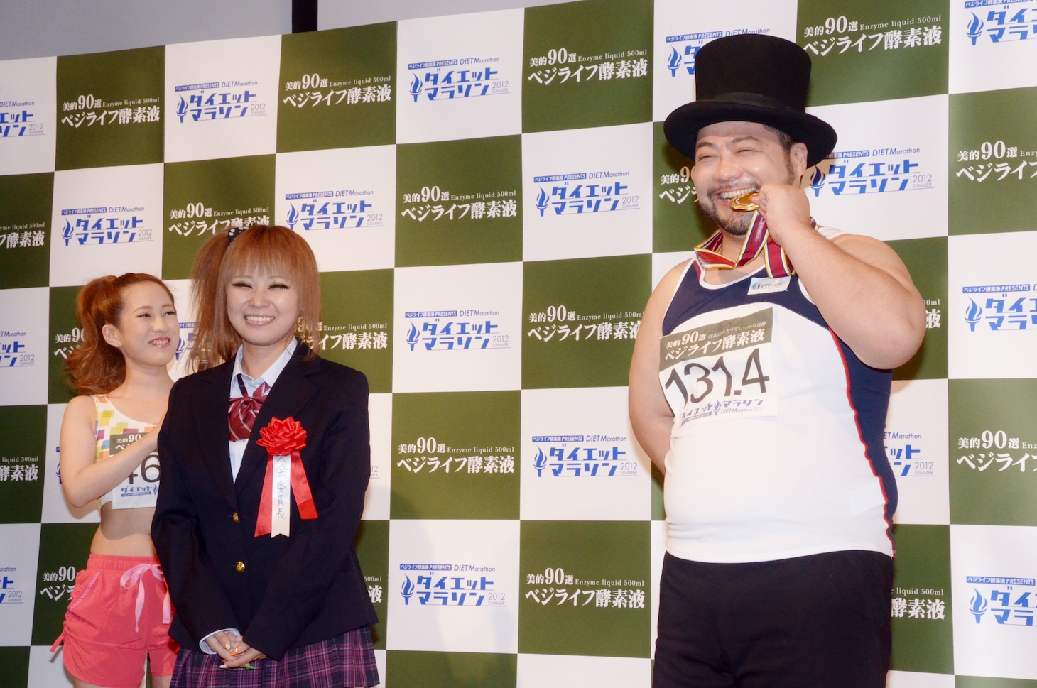 自らも「ベジライフ酵素液」を使ったダイエットを実践した「ダイエットマラソン2012」実行委員長・浜田ブリトニー（左）と、ブリトニーから授与されたメダルをかじる山田ルイ53世（右）。