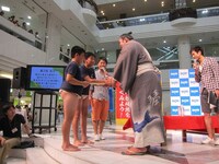 クイズに正解して琴奨菊から手形付きサインをもらう子供達。その子供のメガネをいじる菅。