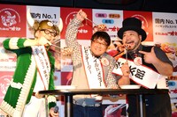 「イカのワイルド焼き」に刻まれている「W」の文字をカメラマンに見せる3人。