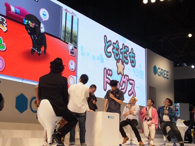 「よしもと×グリー バカソウルステージ in TGS2012」の様子。芸人達がアプリ「ともだちドッグス」を体験する場面では、レイザーラモンRGが育ててきた黒パグ犬がステージ上の大画面に映し出された。