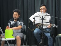 即席のドラムとスティックで演奏する風間カメラマン（左）。