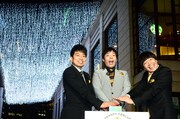 イルミネーションを背景に写真撮影に応じる3人。