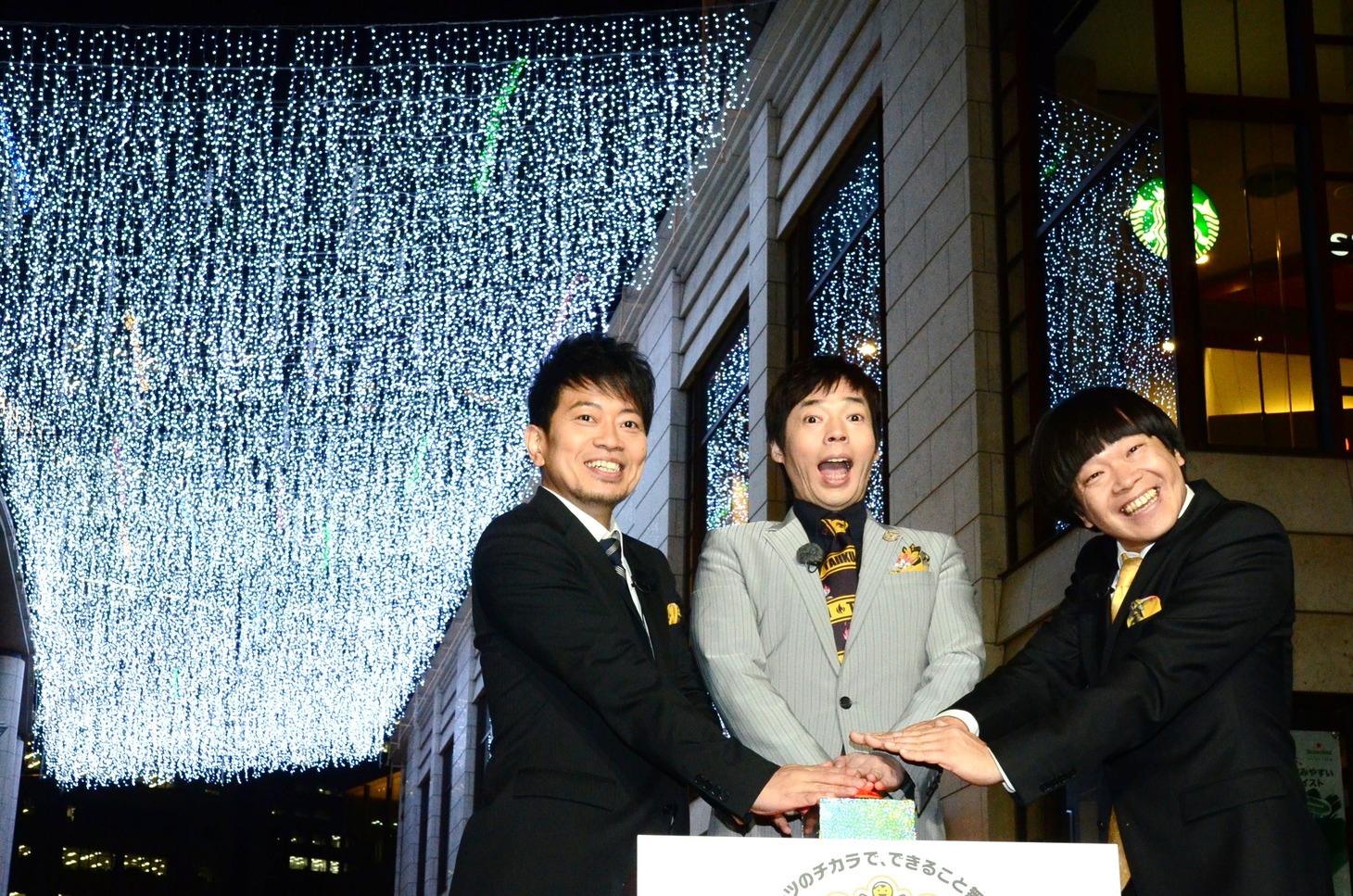イルミネーションを背景に写真撮影に応じる3人。