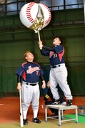 野球ボール型の特大くす玉を打ち割る富澤（右）と、その下で待ち構える伊達（左）。