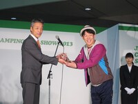 「第一回 キャンピングカーアワード」のトロフィーを満面の笑みで受け取るヒデ。