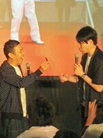 大使の名刺を吉村に嬉しそうに見せる岡村。