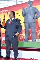 作中で愛用する水筒を手に、石像と同じポーズを取るホンジャマカ石塚。