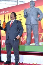 作中で愛用する水筒を手に、石像と同じポーズを取るホンジャマカ石塚。