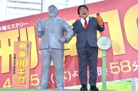 自らの石像を横に写真撮影に応じるホンジャマカ石塚。