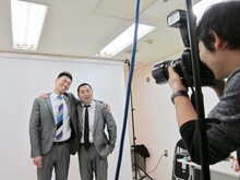 照れながら初めてのスーツの宣材写真撮影を行うレイザーラモン。まずはジャルジャル風に肩を組んで見る。