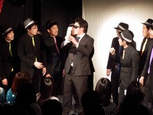 罰ゲーム執行人から封筒を渡されるピテカントロプス（左）。