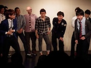 拳銃で撃たれ腹を抑える小宮(手前左)と「いつかのメリークリスマス」を歌い始める相田(手前右)。