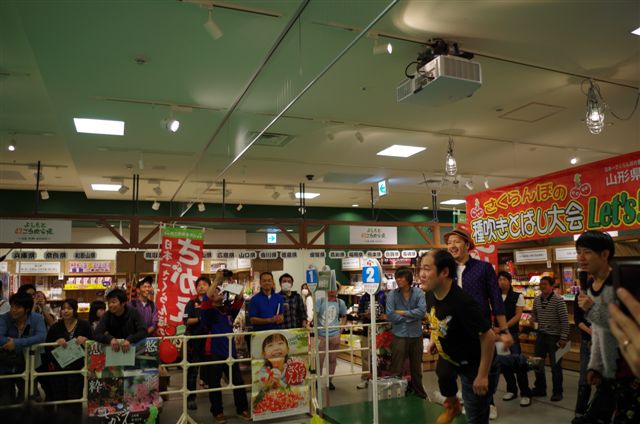 よしもと47ご当地市場にて行われた山形県寒河江市のご当地イベント「さくらんぼの種吹きとばし大会」。(c)吉本興業