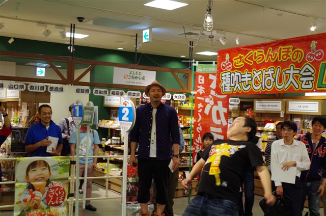 よしもと47ご当地市場にて行われた山形県寒河江市のご当地イベント「さくらんぼの種吹きとばし大会」。(c)吉本興業