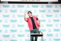 ネタを披露する江西あきよし。旅館の女将さんたちのサインが入った半被で登場。