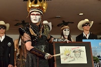 自画像を交えた自作のイラストを紹介するデーモン閣下。