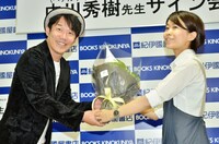 下巻の帯に推薦文を書いた紀伊國屋書店新宿本店の店員から花束を受け取るヒデ（左）。