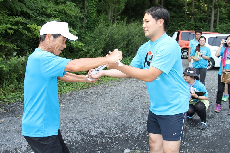 第2走者のアンダーエイジ結城(右)にタスキを渡す間寛平。