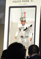 新しくなったAQUOS PHONEの画面だと頭をぶつけることなく通過できると説明するスギちゃん。