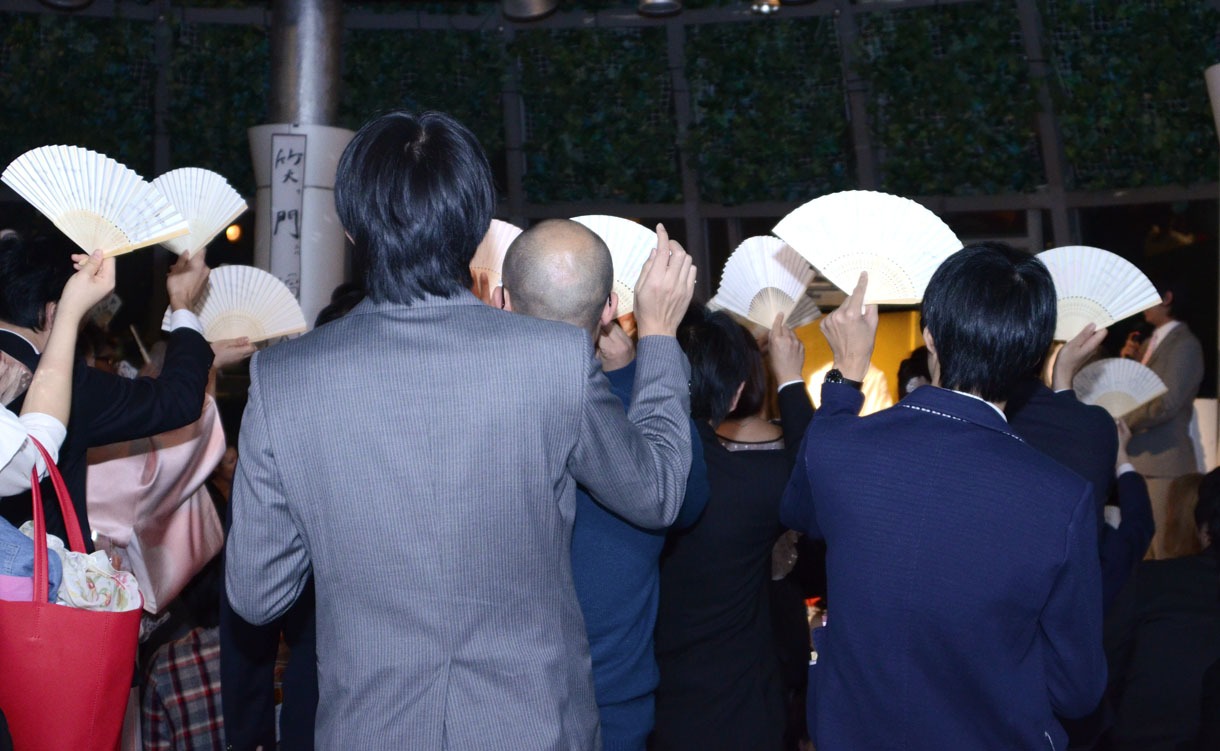 結婚承認の意を表し、「あっぱれ」と書かれた扇子を掲げる参加者たち。