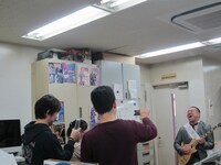 ニール・ショーンモデルの高価なギターを手に「セパレイト・ウェイズ」にのせて、ニール・ショーンあるあるを「バンド変えがち」と歌ったRG。