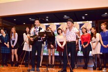 「どびーず」をバックに「イッツ・ロンリー・クリスマス」を披露する、どぶろっく（手前）。