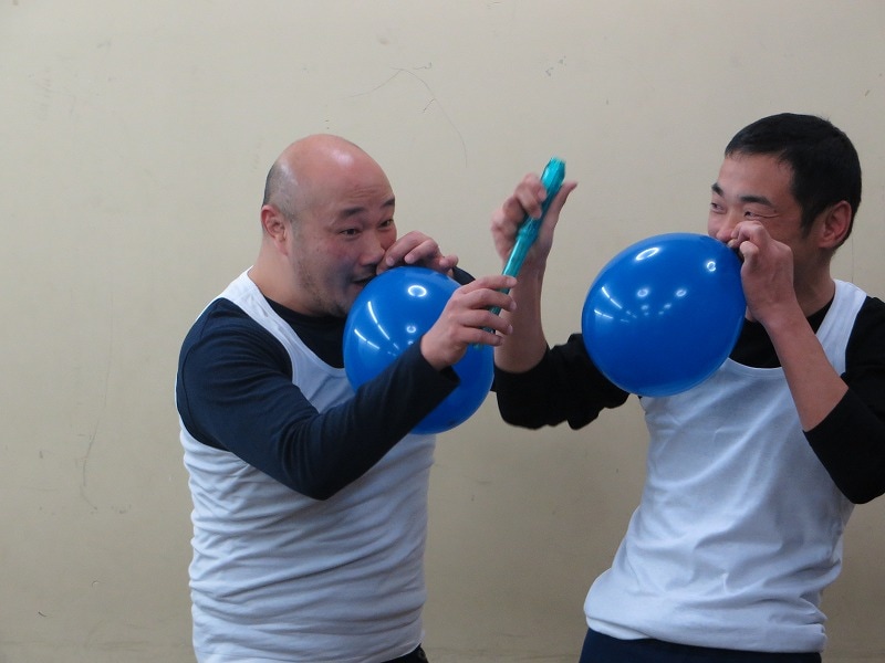 スマホ向けオークションサービス「パシャオク」の「えがお∞（むげんだい）プロジェクト」に「くまだまさしとコラボギャグをやれる！ DVD収録付き」を出品したくまだまさし（左）と、その落札者（右）。