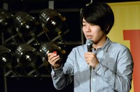 DVD「うしろシティ単独ライブ『うれしい人間』」のタワーレコードオリジナル特典、コント「バンドやろうぜ」に登場する“デスドール”のオリジナルピックキーホルダーを取り出す阿諏訪。