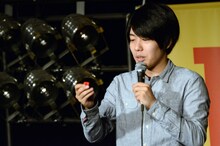 DVD「うしろシティ単独ライブ『うれしい人間』」のタワーレコードオリジナル特典、コント「バンドやろうぜ」に登場する“デスドール”のオリジナルピックキーホルダーを取り出す阿諏訪。