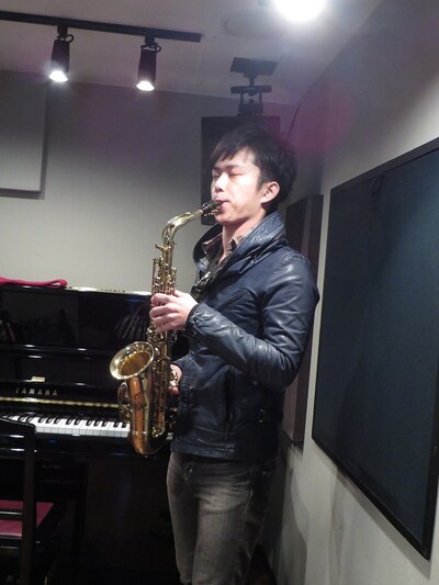 スマホ向けオークションサービ「パシャオク」の「西村ヒロチョがロマンティックに初詣へエスコートする権利」で、ロマンチックにサックスを吹く西村ヒロチョ。