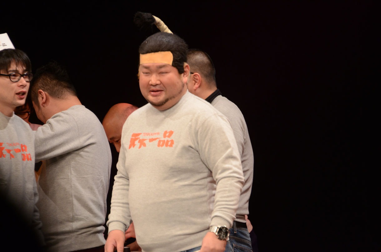 天下一品グッズを使ったモノボケに挑戦する東京ダイナマイト・ハチミツ二郎。