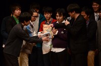 コメンテーター賞として米粒写経のサンキュータツオから米をもらう一服ピストルズ。