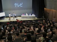 新栄電機のCMについて観客の男性と盛り上がるひとり。