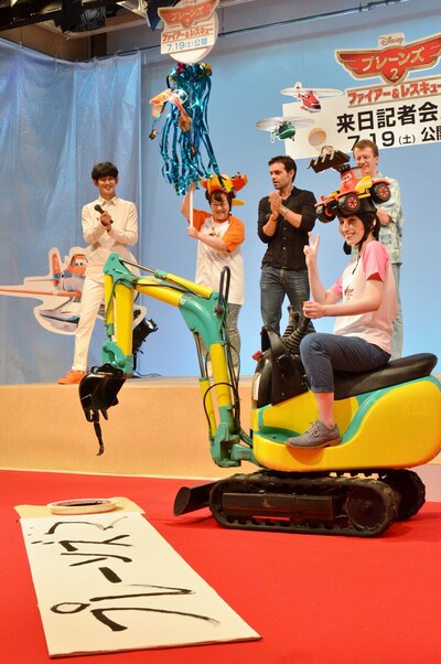 映画「プレーンズ2／ファイアー＆レスキュー」の記者会見イベントで、小型のショベルカーを操縦して書道に挑んだハリセンボンはるか（手前）。