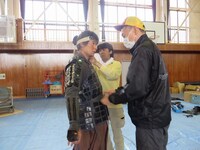 撮影が終了し2人がかりで甲冑を脱がせてもらう吉村。