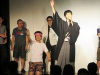 開会宣言をする三福と早着替えに失敗した武田。