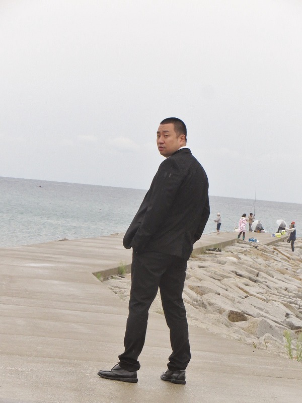 海をバックにポーズを決めるRG。