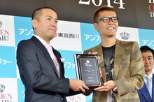 おちまさと（右）から盾を贈呈されるタカアンドトシ・トシ（左）。