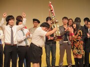 エアギター世界大会で優勝した名倉七海からトロフィーを受け取るタイムマシーン3号。