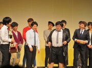 日刊スポーツからの副賞であるミズノ｢SUPERSTAR｣のウォームアップベンチコートを羽織るタイムマシーン3号の関。