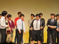 日刊スポーツからの副賞であるミズノ｢SUPERSTAR｣のウォームアップベンチコートを羽織るタイムマシーン3号の関。