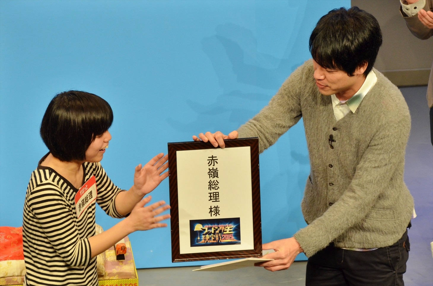 優勝が決まり、麒麟・川島（右）から名前入りの「楽屋バリ」を手渡される、すぽっと赤嶺総理（左）。