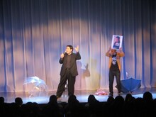 「最後の雨」を歌う中西保志ことセブンbyセブン玉城と、補足説明をするセブンbyセブン宮平。