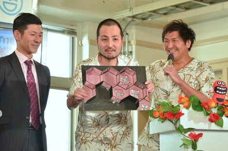 「沖縄おもろおばけ屋敷」の模型を紹介するスリムクラブ内間（中央）。