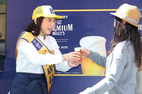 来場客にビールを手渡す椿鬼奴。