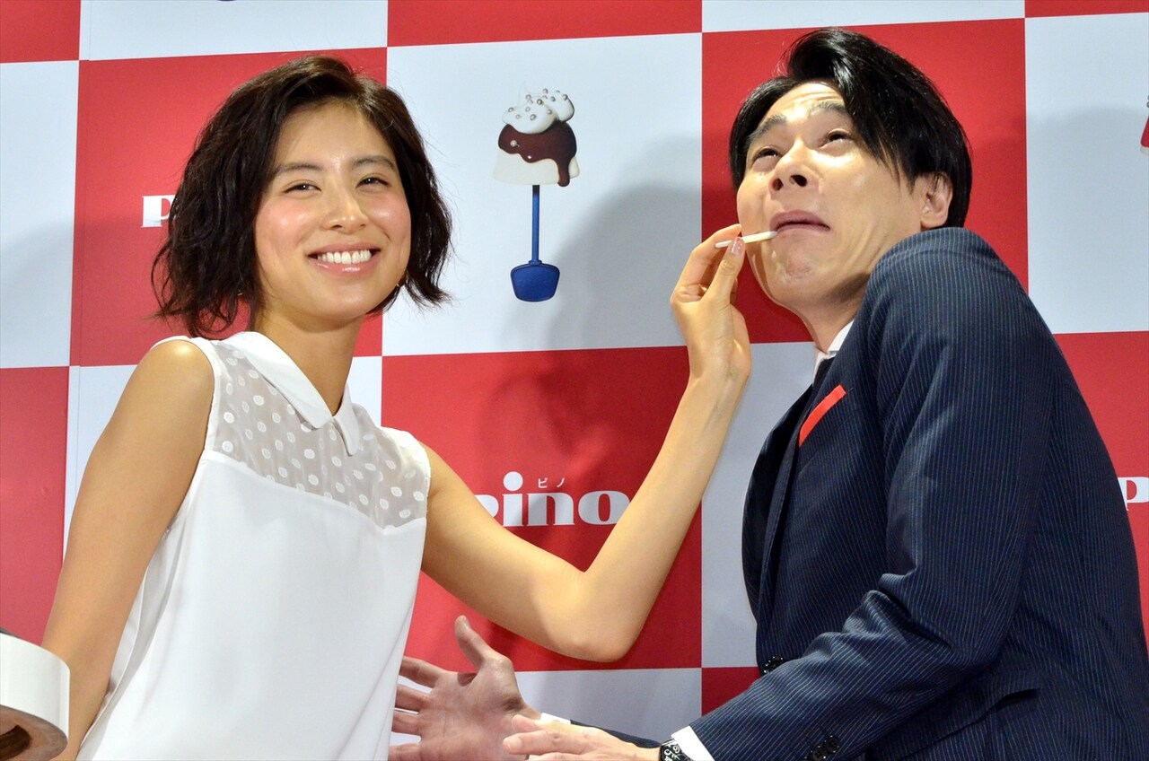 「ピノフォンデュカフェ」のオープニング記念セレモニーで、ラブリ（左）にピノフォンデュを口に運んでもらう平成ノブシコブシ吉村（右）。