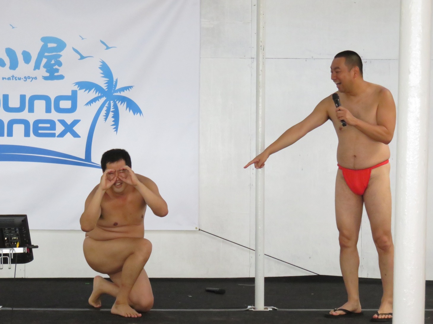 ライフセーバーの全裸に見えるポーズを披露する安村（左）。