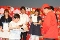 受賞者からお菓子をプレゼントされる山田花子。