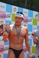 囲み取材に応じる春日。